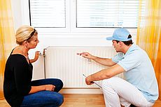 Symbolhaftes Bild einer Frau und eines Handwerkers vor einer Heizung